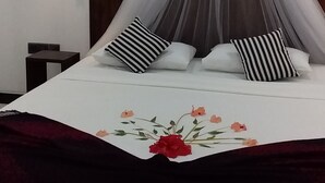 A bed with a canopy, striped pillows, a bedside table, and a wall-mounted light fixture. - Venus Paradise (Sigiriya)