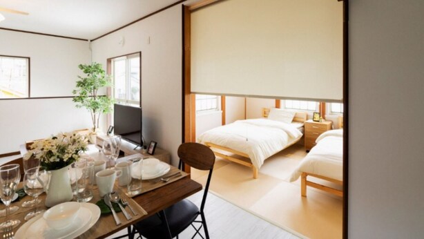 Ein modernes Hotelzimmer mit einem großen Bett, einer Essecke mit Tisch für zwei Personen und einem großen Fenster mit Aussicht.