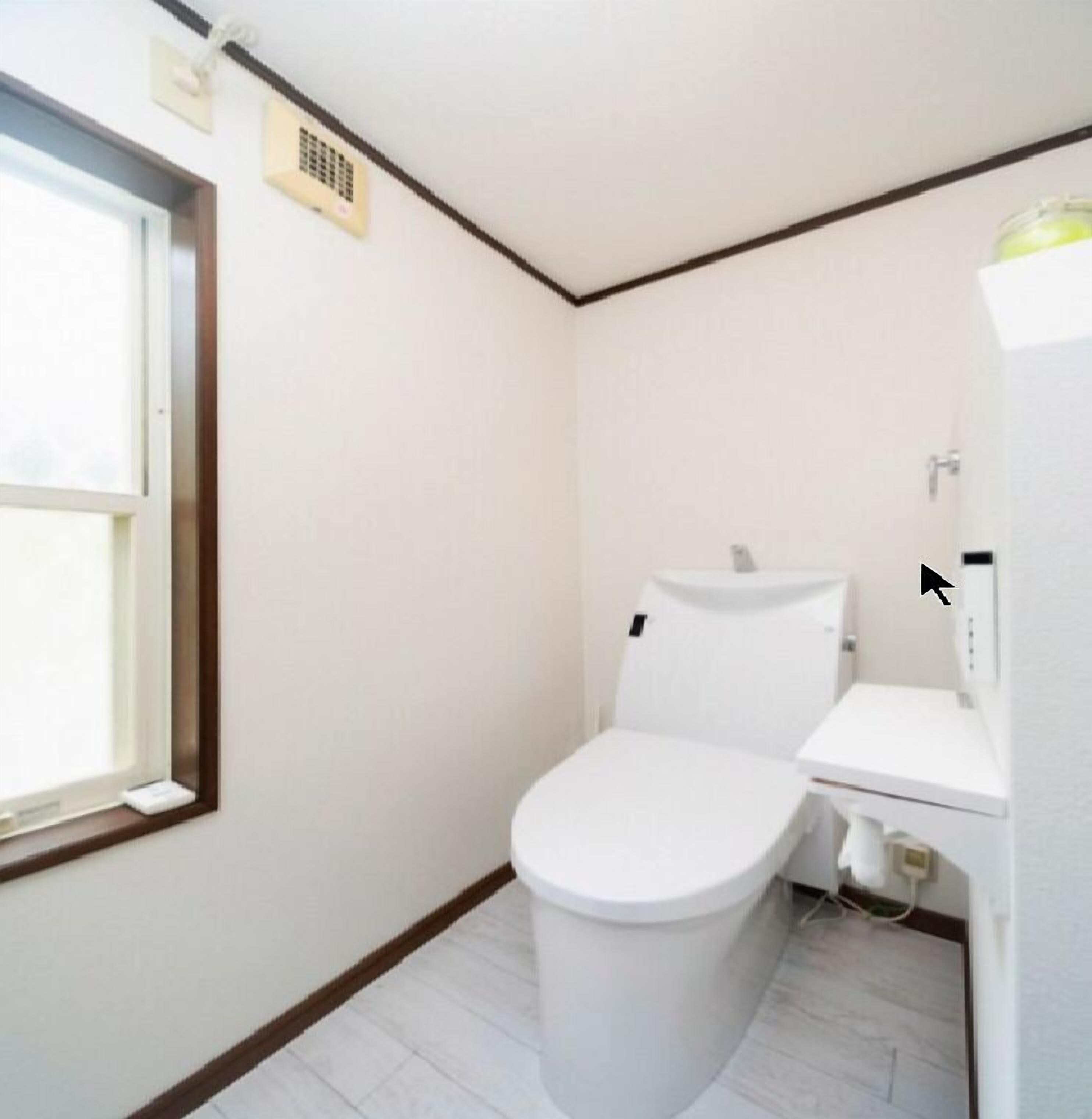 A small, compact bathroom with a toilet, sink, and window.