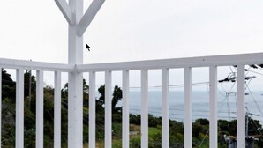 Ein weißer Balkon mit Blick auf das Meer und Stromleitungen.