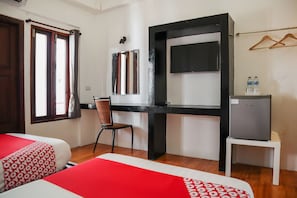 A hotel room with two beds, a chair, a desk, a television, and a small refrigerator. - OYO 778 21 Poshtel (Phuket)
