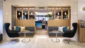 Een moderne lobby met twee banken, een receptiebalie en uitzicht op de eetruimte.