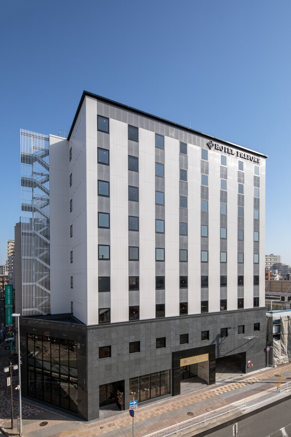 A modern hotel building with a prominent entrance and a clear sky. - Hotel Prefort Nishiakashi (Akashi)