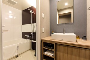 A modern bathroom with a bathtub, shower, and a vanity with a sink and mirror. - Hotel Prefort Nishiakashi (Akashi)