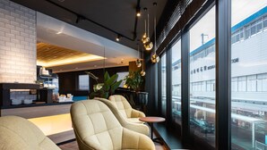 Een moderne loungeruimte met comfortabele zitplaatsen, een koffiehoek en grote ramen met uitzicht op de stad.