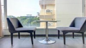 A modern room with two grey chairs and a small round table. - Hotel Aura (Mumbai)