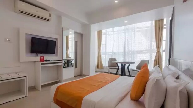 A hotel room with a bed, a desk, a TV, and a window with curtains. - Hotel Aura (Mumbai)