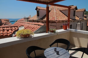 A balcony with terracotta-tiled roofs, potted plants, and outdoor seating. - Dolce Vita Apartments (Split)