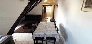 A dining area with a table set for four, a sofa, and a staircase. - Dolce Vita Apartments (Split)