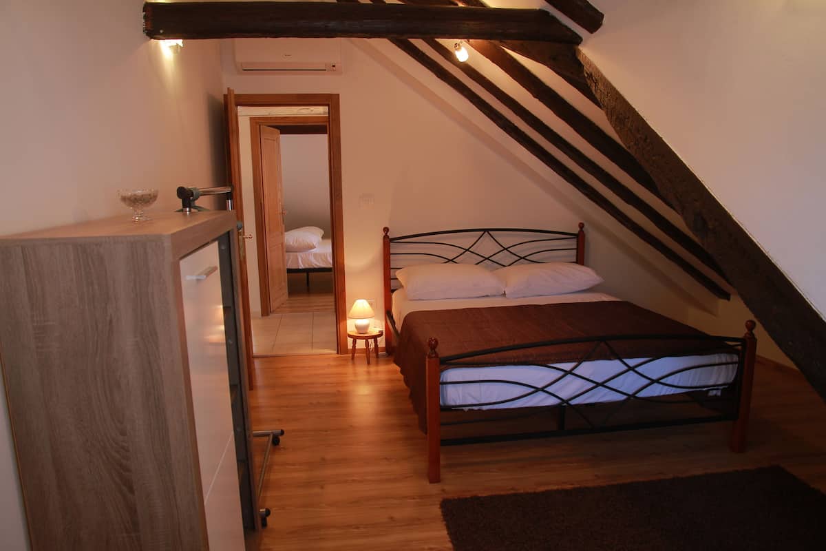 Une chambre avec un lit en bois, une table de chevet avec une lampe et une commode en bois.