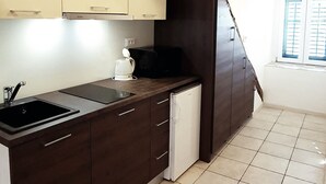 Una cocina con armarios de madera oscura, encimera blanca y suelo de baldosas.