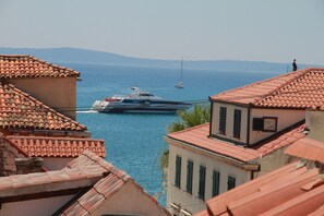 A coastal town with terracotta-roofed buildings, a marina with boats, and a clear view of the sea. - Dolce Vita Apartments (Split)