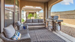 Un patio al aire libre con un sofá, sillas de mimbre y una parrilla.