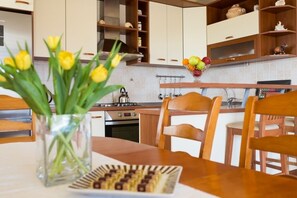 A modern kitchen with wooden cabinets, a stove, and a dining area with a table and chairs.