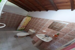 Bathroom features a toilet, sink, and shower area with a curtain and soap dispenser.