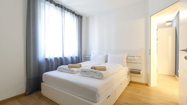 Ein modernes Hotelzimmer mit einem großen Bett, einem Nachttisch und einem Kleiderschrank.