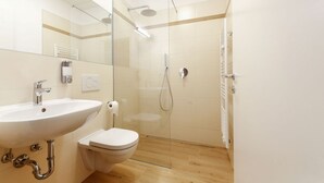 Ein modernes Badezimmer mit einer Duschkabine, einem weißen Waschbecken und einer Toilette.