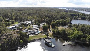 An aerial view of a lakeside property with modern buildings, a dock, and a boat.