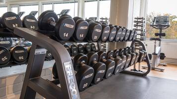 Ett gym med flera rader av hantlar, där varje hantel är märkt med sin vikt.