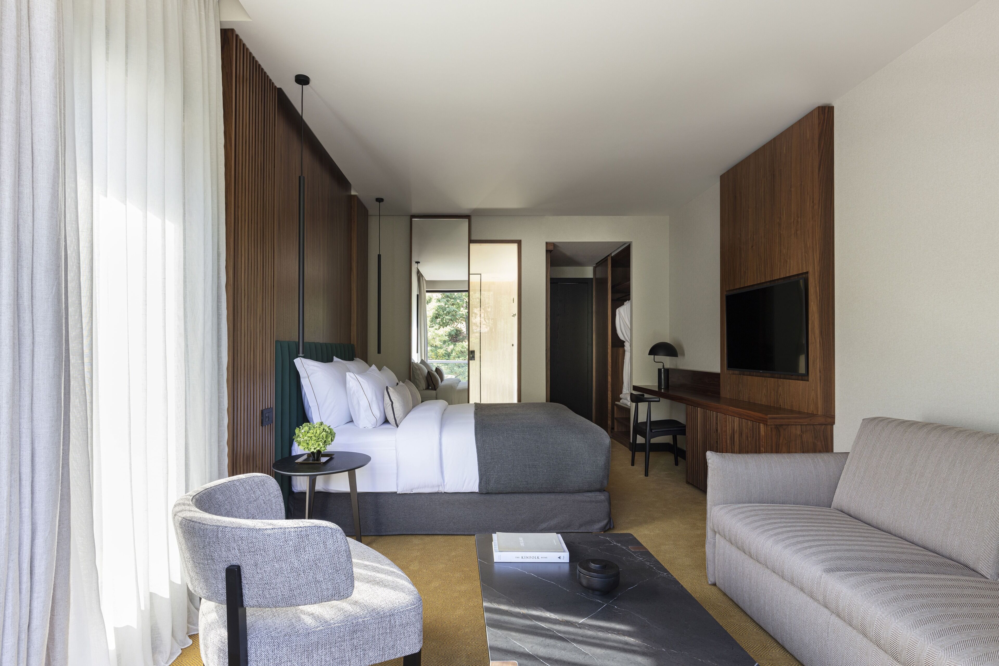 Habitación de hotel con cama, sofá, escritorio y televisión.