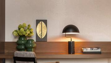 A modern desk with a lamp, a chair, and a vase of flowers.