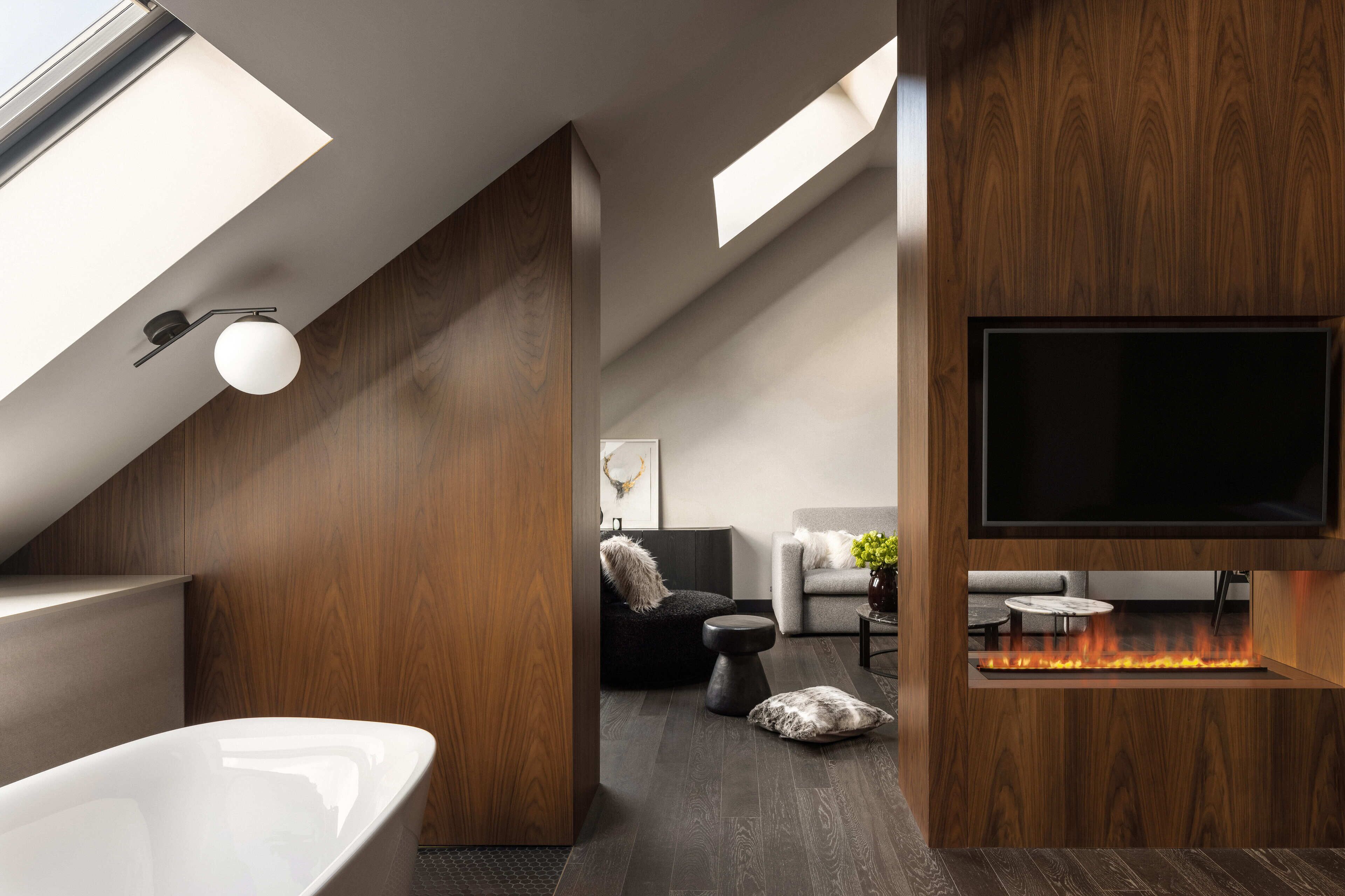 A modern interior with a freestanding bathtub, a fireplace, and a flat-screen TV mounted on a wooden wall.