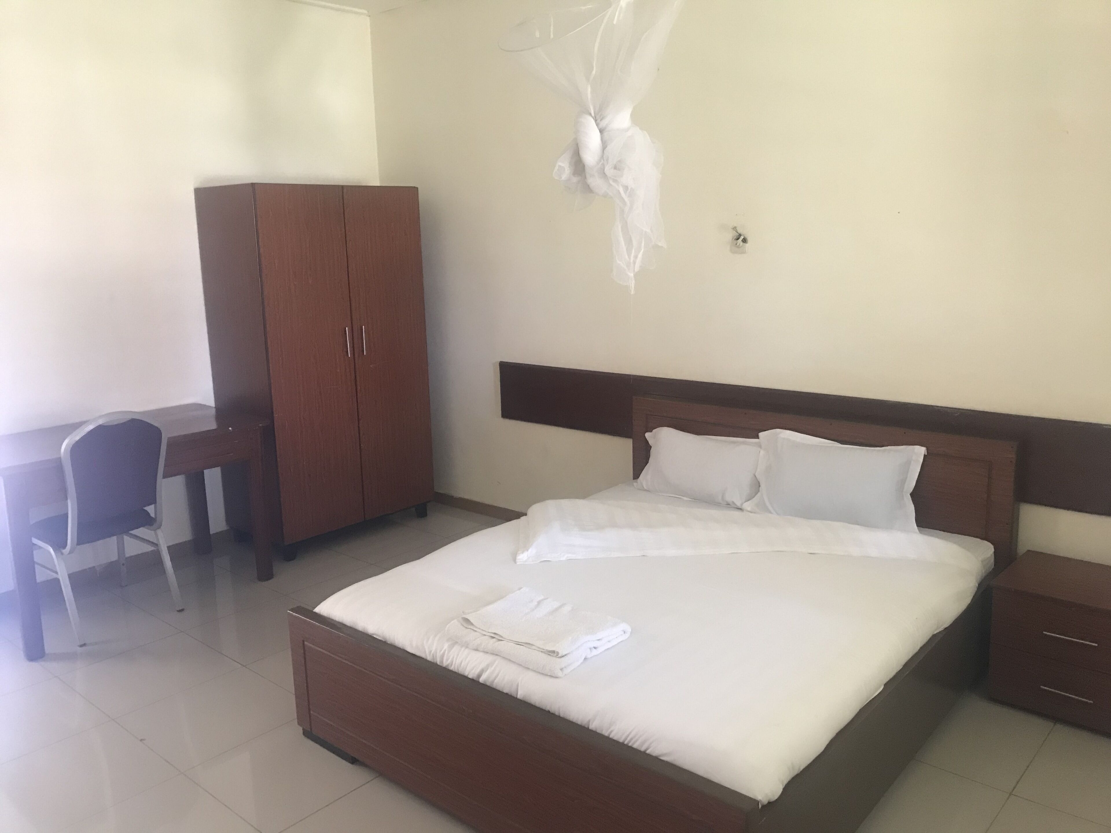 A neatly arranged bedroom with a bed, a desk, and a wardrobe.