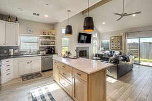 A modern kitchen with a central island, built-in cabinets, and a dining area with a sofa. - 'Uncorked Ranch' Hill Country Home: 1 Mi to Winery (Fredericksburg)