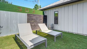 A patio with two lounge chairs, a wooden fence, and a building with the number '303' on it.