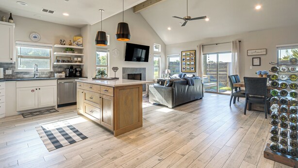 A spacious kitchen with wooden cabinets, a central island, pendant lighting, and a dining area with a sofa and chairs.