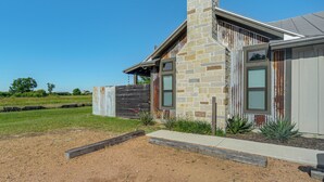 A modern house with a stone chimney, a wooden fence, and a well-maintained lawn.