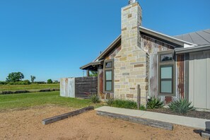 Une maison moderne avec une cheminée en pierre, une clôture en bois et une pelouse bien entretenue.