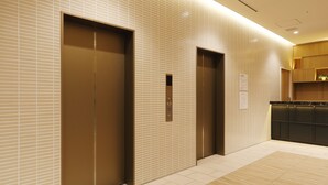 A modern elevator area with two elevators and a reception desk. - JR Inn Sapporo Kita 2jo (Sapporo)