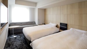 A hotel room with two beds, a sofa, a small round table, and a large window. - JR Inn Sapporo Kita 2jo (Sapporo)