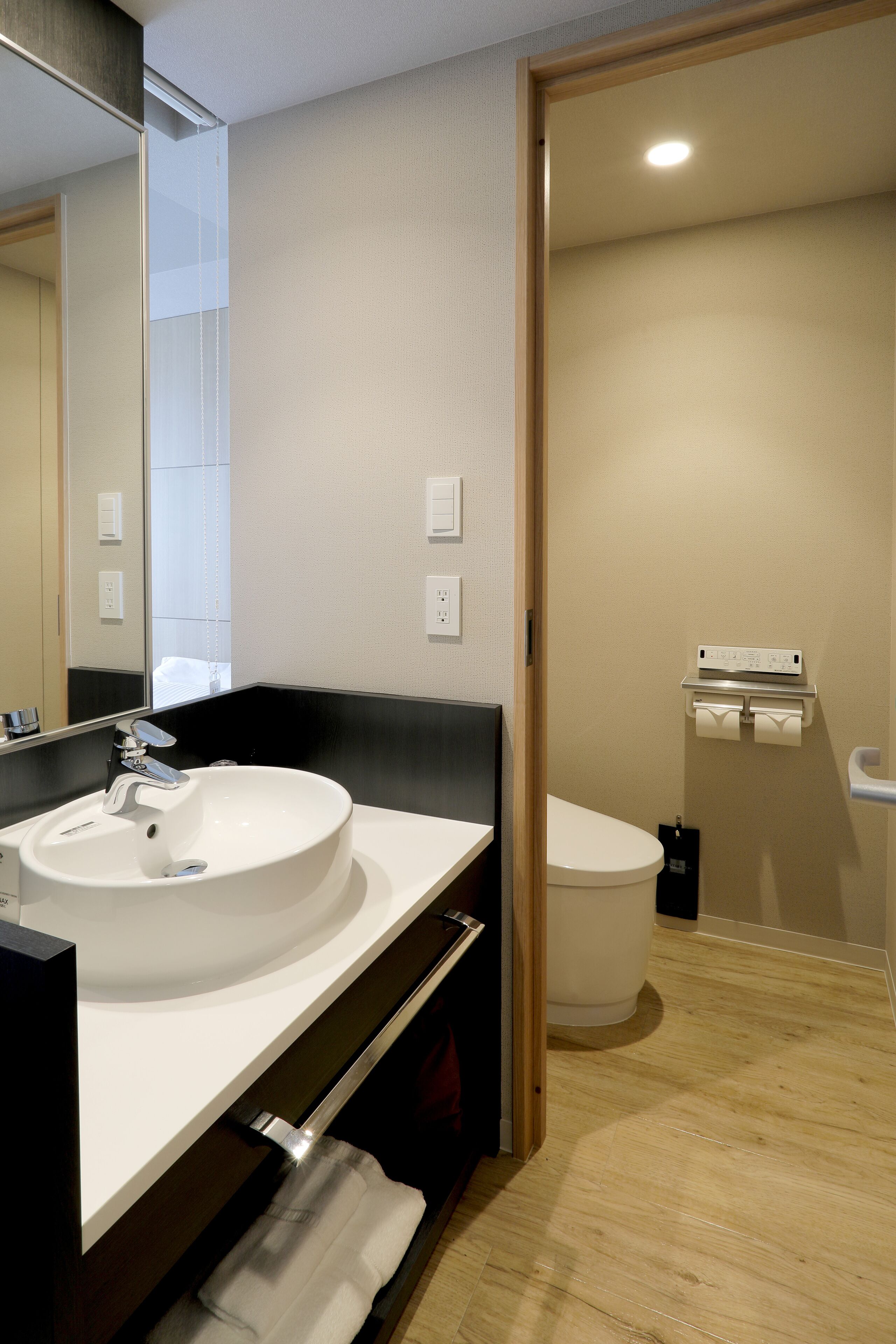A modern bathroom with a white sink, mirror, and toilet.