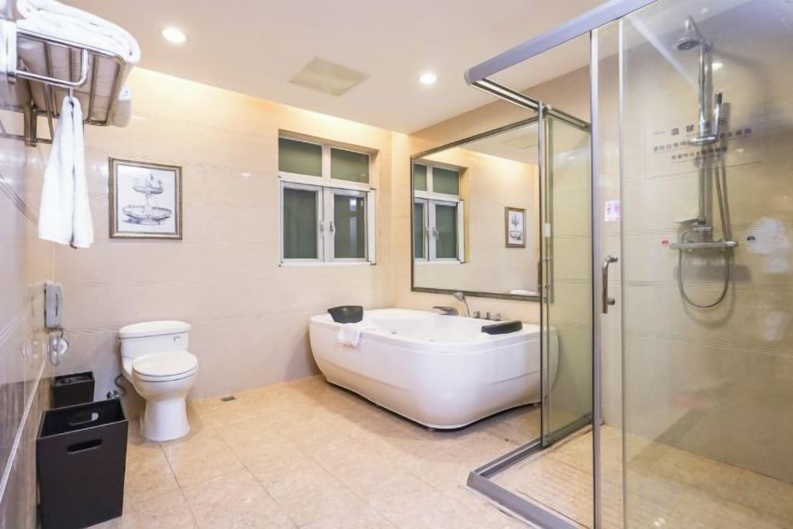 Een moderne badkamer met toilet, bad en een douchecabine met glazen wanden.