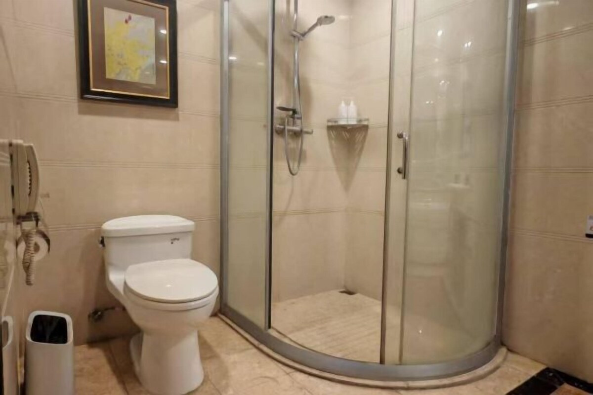 A bathroom with a toilet, a glass-enclosed shower, and a framed map on the wall.