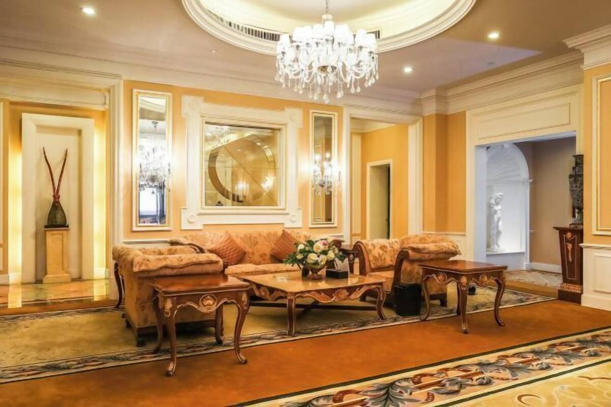 Um quarto luxuoso com um amplo sofá, um lustre e um tapete estampado.
