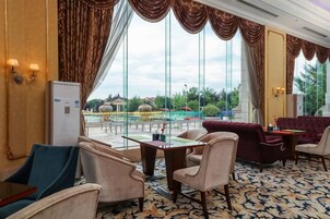 Un vestíbulo de hotel con un amplio ventanal, un sofá, sillas y una mesa.