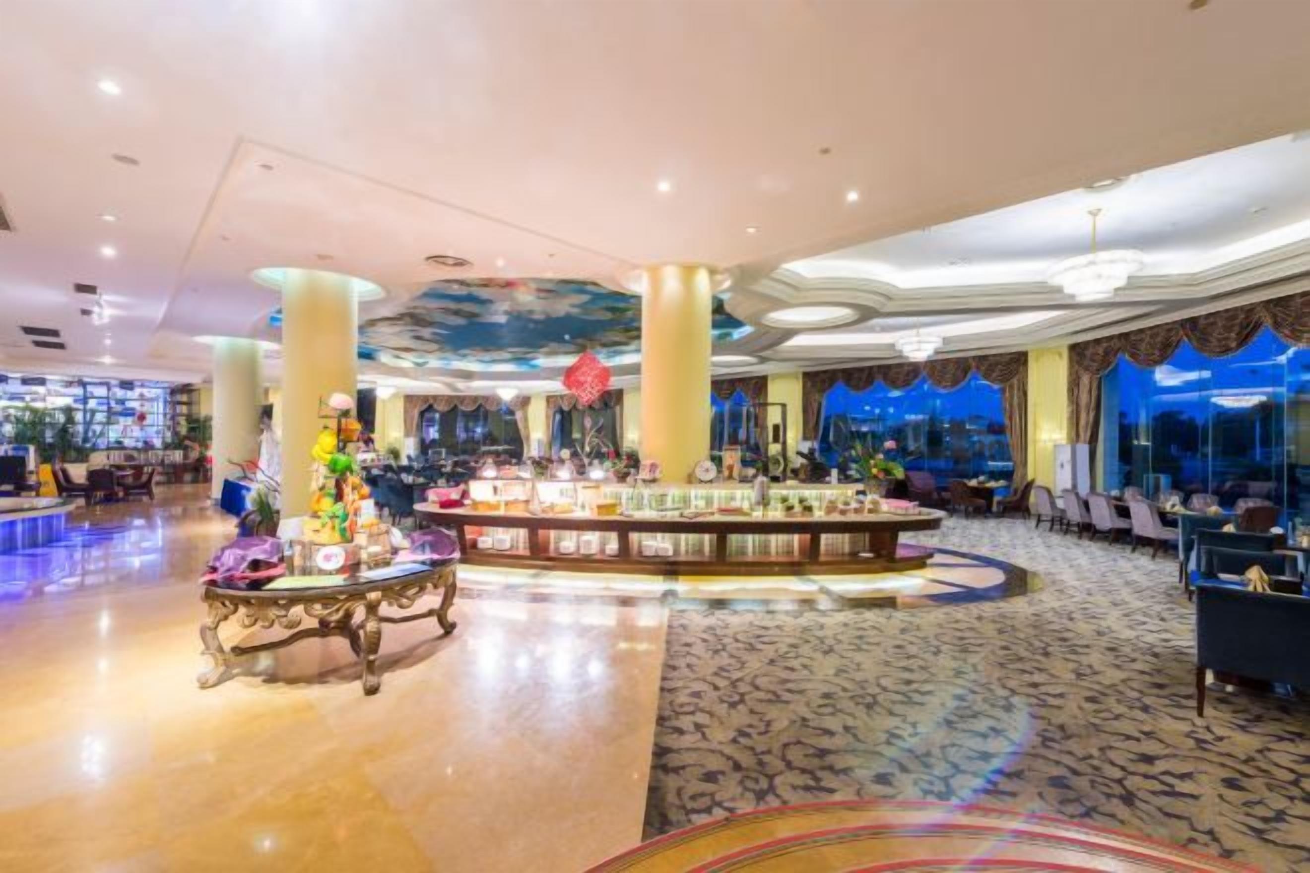 Eine Hotellobby mit einer zentralen Bar, Sitzgelegenheiten und einem gemusterten Teppich.