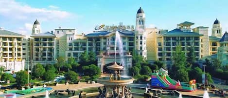 A hotel with a central fountain, multiple water features, and a colorful play area.