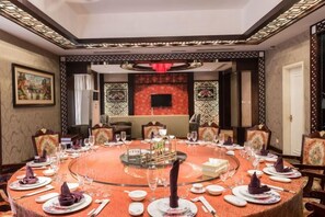 A round dining table with multiple chairs, a central decorative piece, and a television screen in the background. - City Phoenix Hotel, Europe, Country Garden, Chuzhou (Chuzhou)