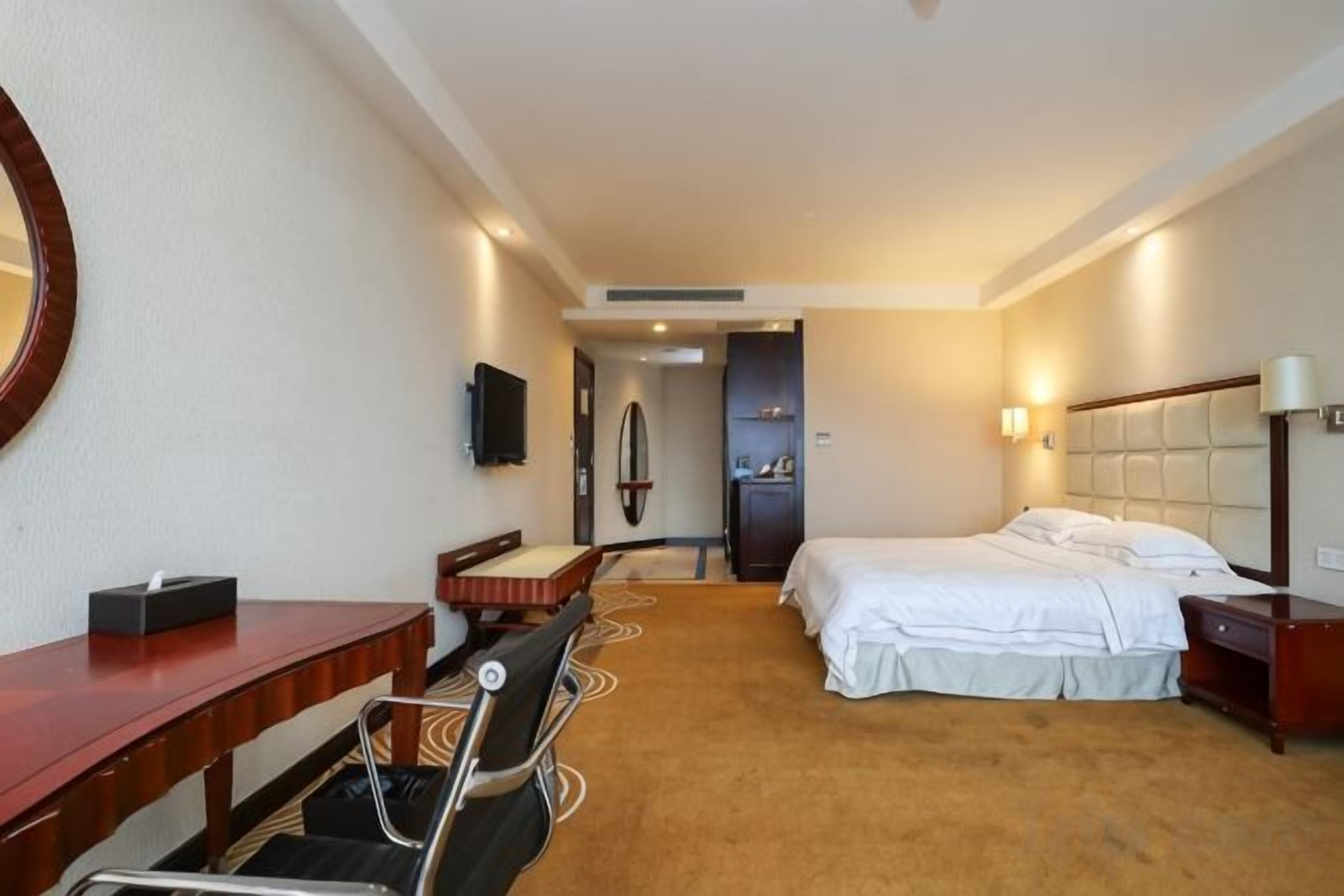 Una habitación de hotel con cama, escritorio, silla y televisor.