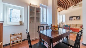 A dining area with a wooden table, chairs, a cabinet with glass doors, and a window. - Three bedrooms in world-famous Via Giulia - Wifi, A/C, Washing machine (Roma)