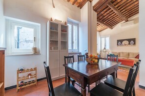 A dining area with a wooden table, chairs, a cabinet with glass doors, and a window.
