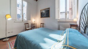 A bedroom with a bed, two windows, a painting, a floor lamp, and a radiator. - Three bedrooms in world-famous Via Giulia - Wifi, A/C, Washing machine (Roma)