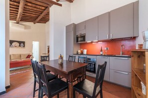 A modern kitchen with grey cabinets, a wooden dining table, and a red backsplash. - Three bedrooms in world-famous Via Giulia - Wifi, A/C, Washing machine (Roma)