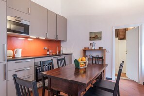 A modern kitchen with grey cabinets, a wooden dining table, and a fruit basket. - Three bedrooms in world-famous Via Giulia - Wifi, A/C, Washing machine (Roma)