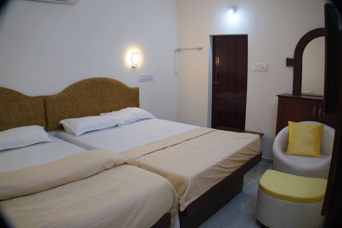 A hotel room with two beds, a chair, a mirror, and a door.