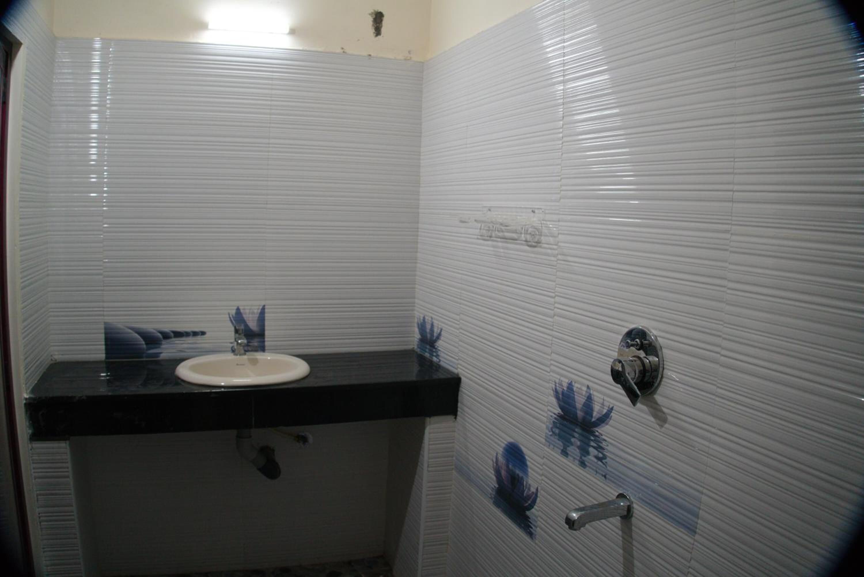 A small bathroom with a white sink, black countertop, and a toilet.